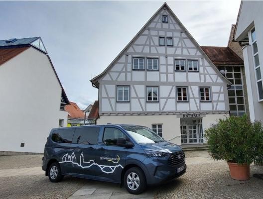dunkelblauer Kleinbus vor Rathaus