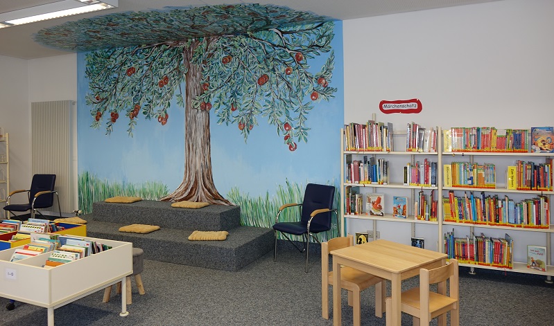 Innenansicht Bibliothek mit einem Apfelbaum auf der Wand