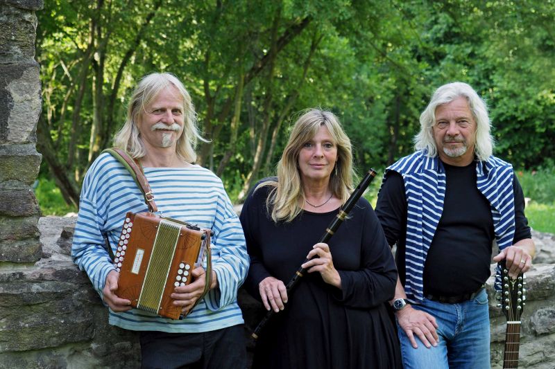 Mann mit Arkodeon, Frau mit Flöte und Mann stützt sich auf Gitarre
