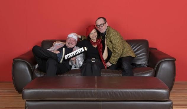 zwei Männer eine Frau auf einer braunen Ledercouch