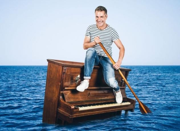 Mann auf Klavier im Meer mit Ruder in Hand